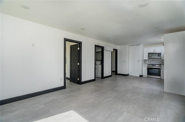 unfurnished living room featuring baseboards and finished concrete floors