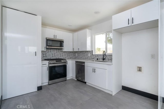 kitchen with light countertops, white cabinets, a sink, appliances with stainless steel finishes, and backsplash