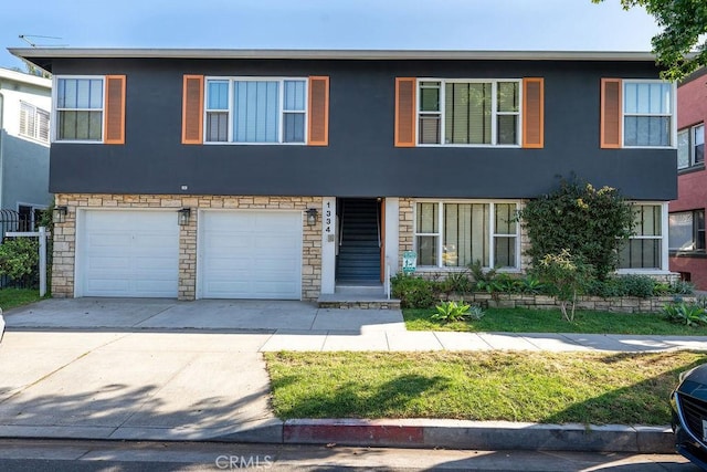 view of property with a garage, stucco siding, driveway, and stone siding