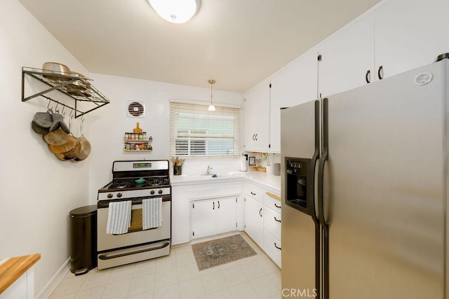 kitchen featuring light countertops, white cabinetry, a sink, appliances with stainless steel finishes, and decorative light fixtures