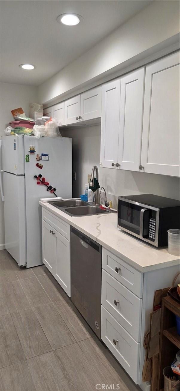 kitchen with white cabinets, stainless steel appliances, a sink, and light countertops