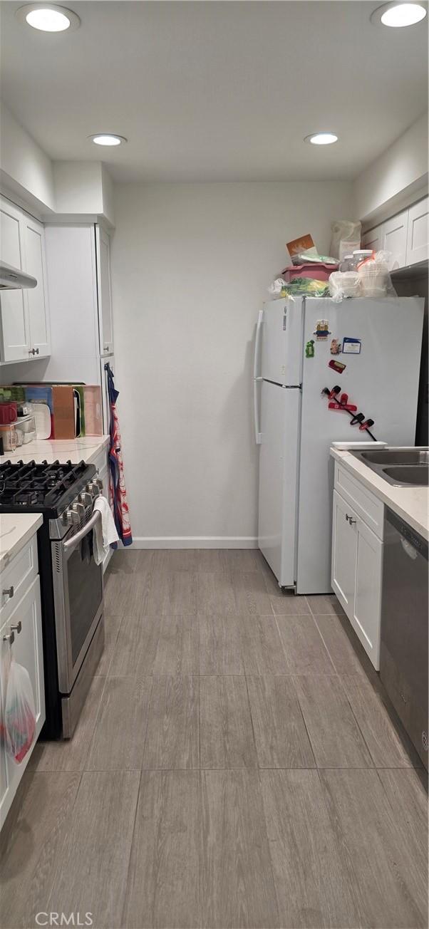 kitchen featuring white cabinets, appliances with stainless steel finishes, a sink, and light wood-style floors
