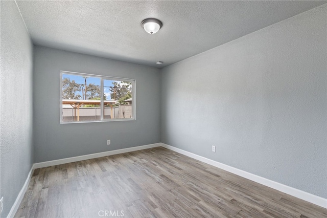 unfurnished room featuring baseboards, a textured ceiling, and wood finished floors