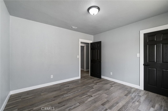 unfurnished bedroom featuring baseboards, visible vents, and wood finished floors
