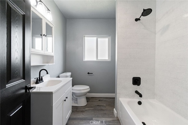 full bathroom featuring wood finished floors, vanity, baseboards, toilet, and washtub / shower combination