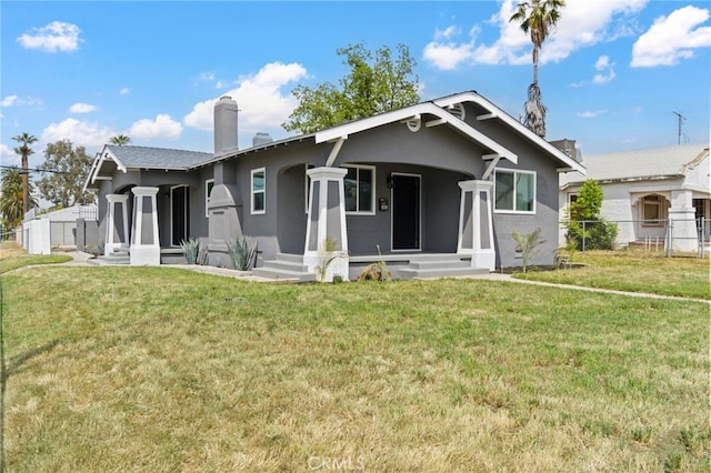 view of front of property with a front lawn, fence, stucco siding, a chimney, and a porch