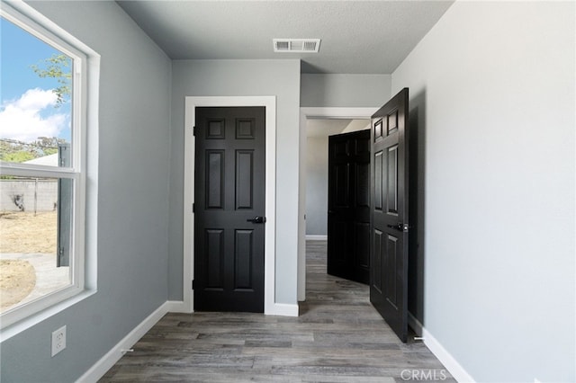 foyer featuring visible vents, a textured ceiling, baseboards, and wood finished floors