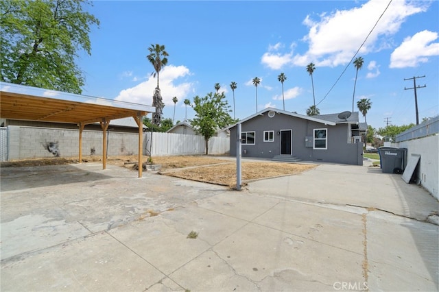 back of house featuring fence, a carport, and stucco siding