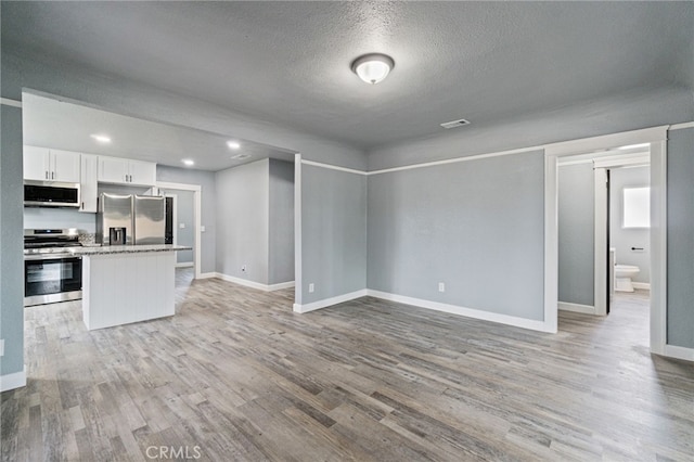 kitchen featuring baseboards, light wood-style flooring, white cabinetry, and stainless steel appliances