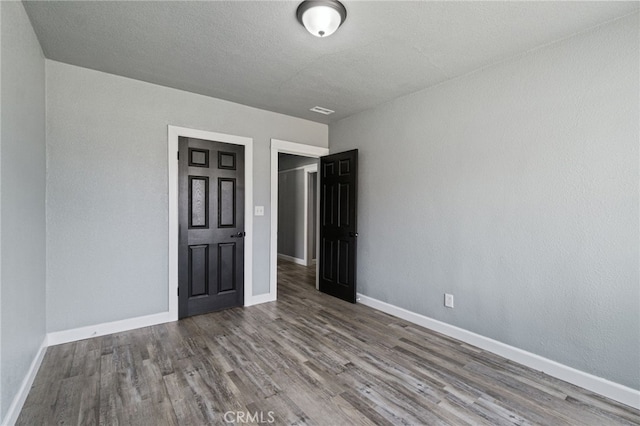 interior space with baseboards, wood finished floors, and visible vents