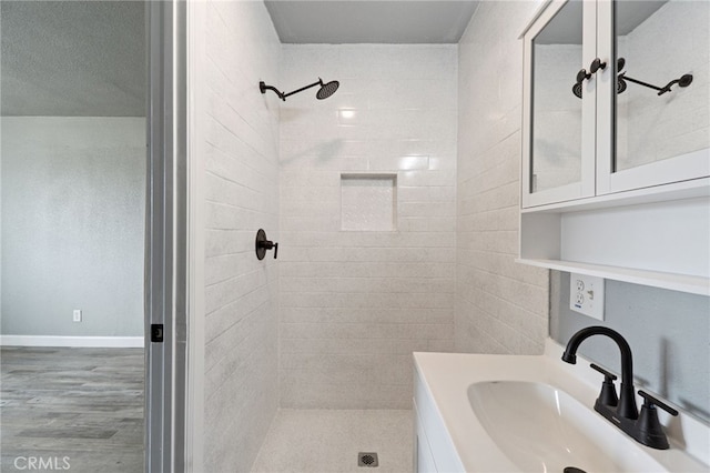 bathroom with a sink, tiled shower, and wood finished floors
