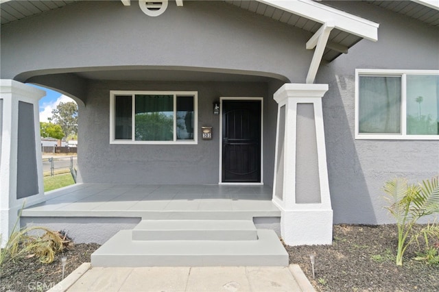 entrance to property featuring covered porch and stucco siding