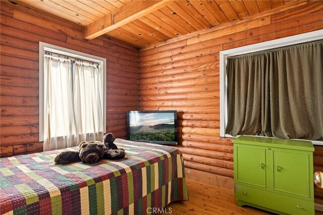 bedroom with beam ceiling, log walls, wood ceiling, and wood finished floors