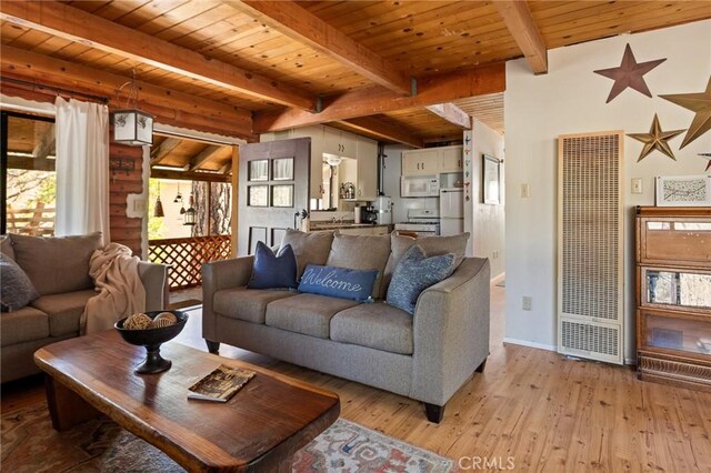 living area with wood ceiling, beam ceiling, baseboards, light wood-style floors, and a heating unit