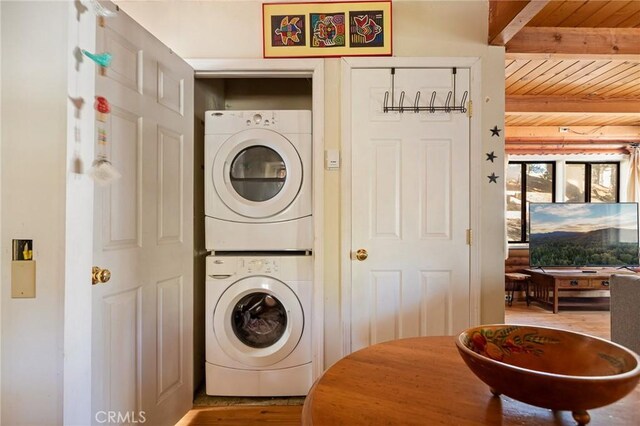 laundry room featuring laundry area, wood finished floors, stacked washer / dryer, and wooden ceiling