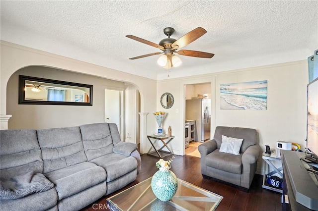 living room featuring arched walkways, ceiling fan, hardwood / wood-style flooring, and a textured ceiling