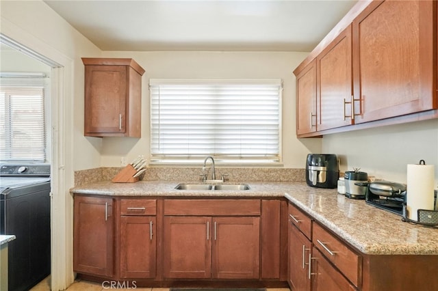kitchen with washer / clothes dryer, brown cabinets, a healthy amount of sunlight, and a sink