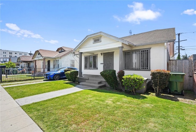 bungalow-style house featuring concrete driveway, fence, and a front lawn