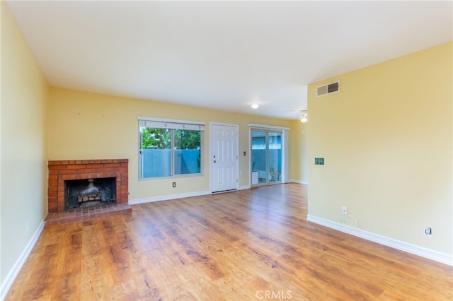 unfurnished living room featuring baseboards, visible vents, and wood finished floors