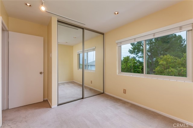 unfurnished bedroom featuring baseboards, light carpet, and a closet