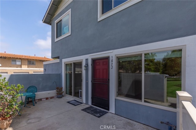 exterior space featuring fence, stucco siding, and a patio area