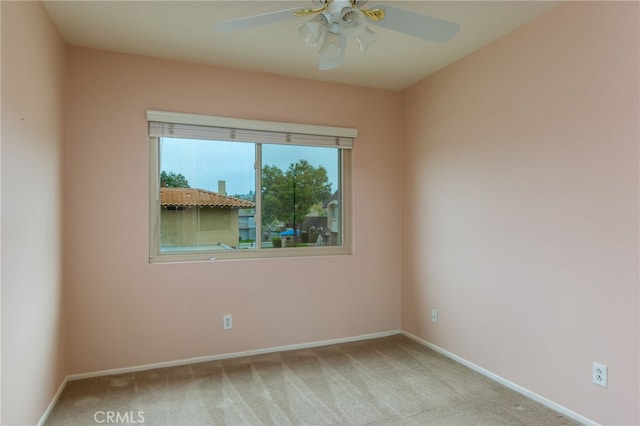 carpeted empty room with a ceiling fan and baseboards