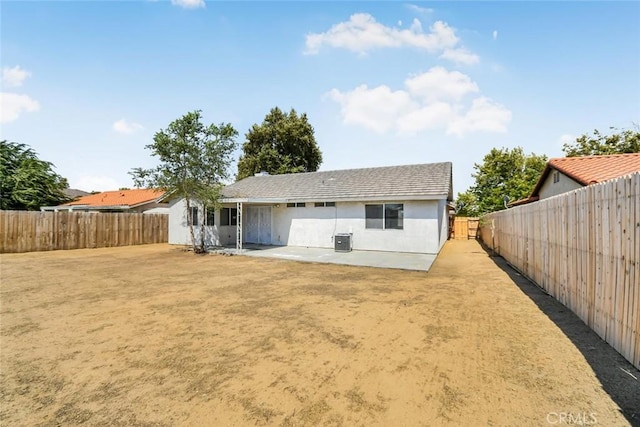 rear view of house featuring a fenced backyard, a patio area, and stucco siding