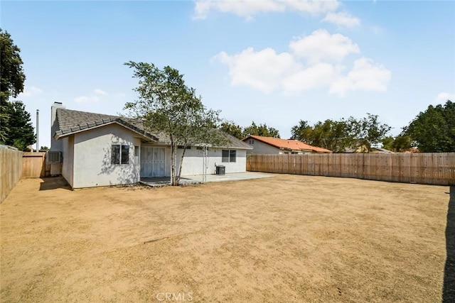 rear view of property featuring stucco siding, a fenced backyard, a chimney, a patio area, and a tiled roof