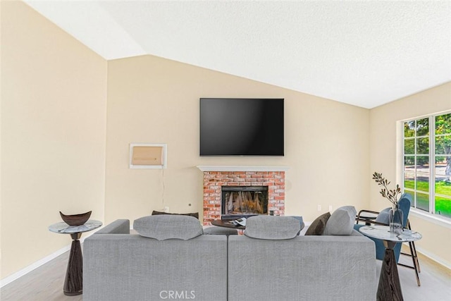 living room featuring baseboards, a brick fireplace, wood finished floors, and lofted ceiling