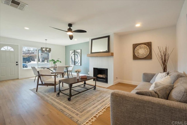 living area featuring a fireplace, a ceiling fan, baseboards, recessed lighting, and visible vents