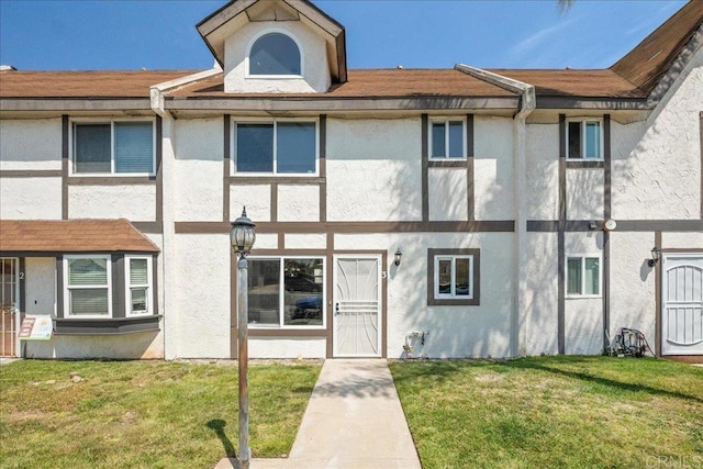 townhome / multi-family property with a front lawn and stucco siding