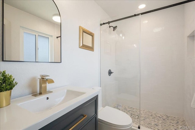 bathroom with vanity, toilet, and tiled shower