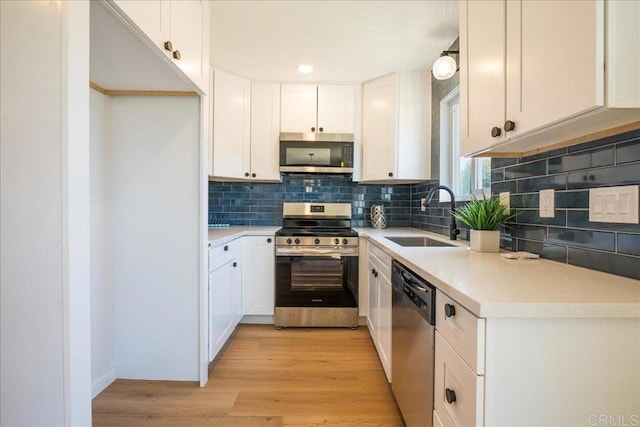 kitchen featuring appliances with stainless steel finishes, a sink, light countertops, white cabinetry, and decorative backsplash