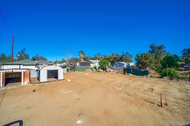 view of yard featuring fence, an outbuilding, and a shed