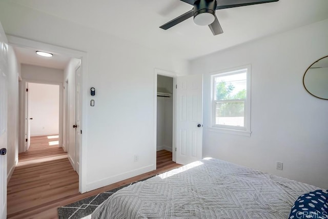 bedroom featuring a ceiling fan, baseboards, wood finished floors, and a closet