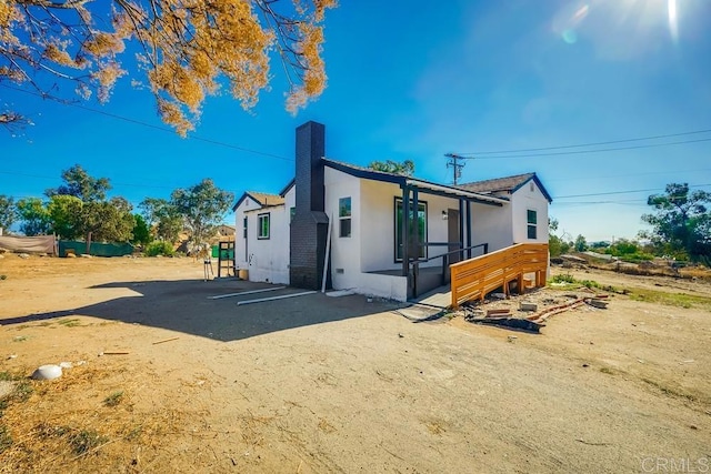 back of property with a chimney and stucco siding