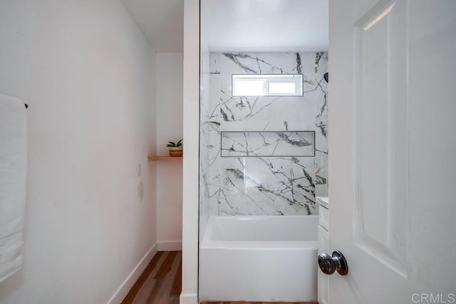 full bathroom featuring baseboards, wood finished floors, and shower / washtub combination