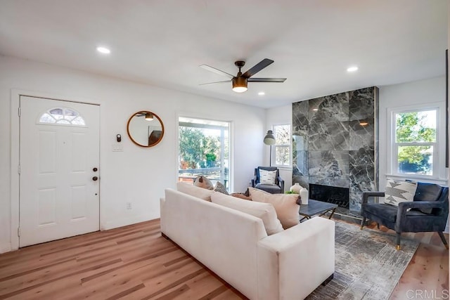 living room featuring a ceiling fan, recessed lighting, a high end fireplace, and light wood-style floors