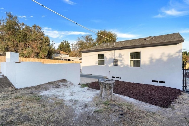 view of side of property with fence and stucco siding