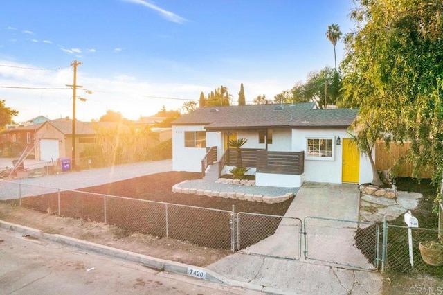 ranch-style home featuring roof with shingles, a gate, a fenced front yard, and stucco siding