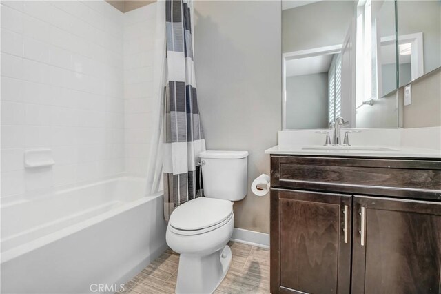 bathroom featuring vanity, baseboards, shower / bath combo, and toilet