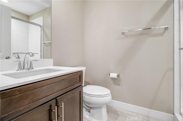 full bath with vanity, wood finished floors, a shower, toilet, and baseboards