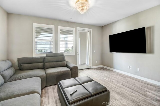 living room with baseboards, light wood finished floors, and a chandelier