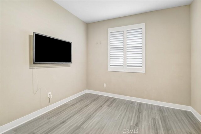 spare room with baseboards and wood finished floors