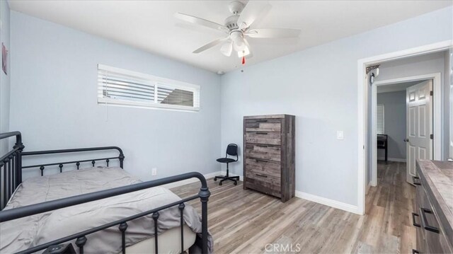 bedroom featuring baseboards, light wood finished floors, and ceiling fan