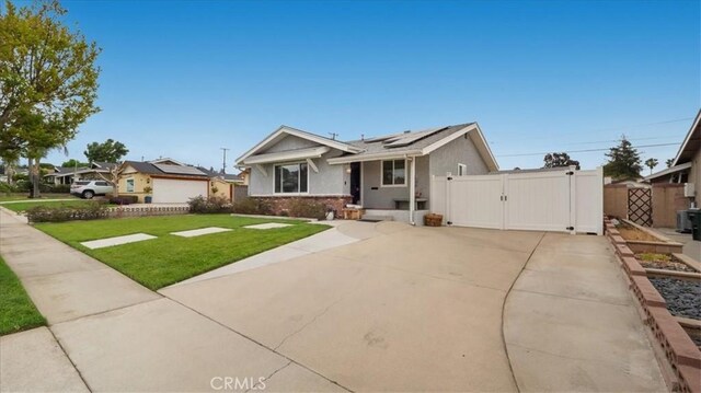 view of front of property featuring solar panels, a front yard, a gate, fence, and stucco siding