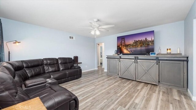 living room with ceiling fan, visible vents, baseboards, and light wood-style floors