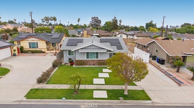 view of front of property with a residential view, roof mounted solar panels, driveway, and a front lawn