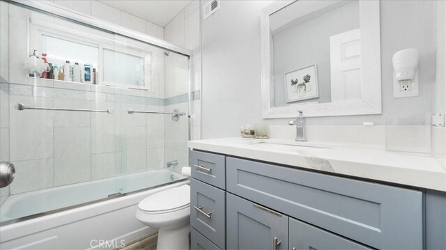 bathroom with vanity, shower / bath combination with glass door, visible vents, and toilet