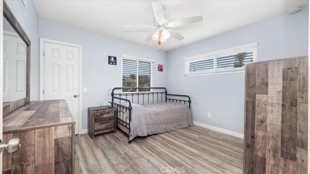 bedroom with baseboards, ceiling fan, and light wood-style flooring